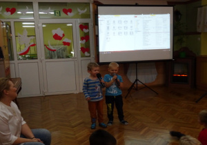Dwóch chłopców z gr. II śpiewa piosenkę, na ekranie wyświetlane są słowa piosenki.